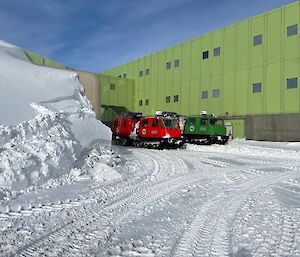 Hagglands parked outside a large green building with large amounts of snow around