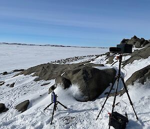 A camera and sound equipment on tripods with rocks and ice in the background
