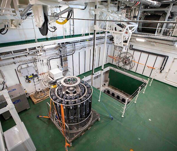 The moon pool room on the ship showing the open shaft and an oceanographic instrument.