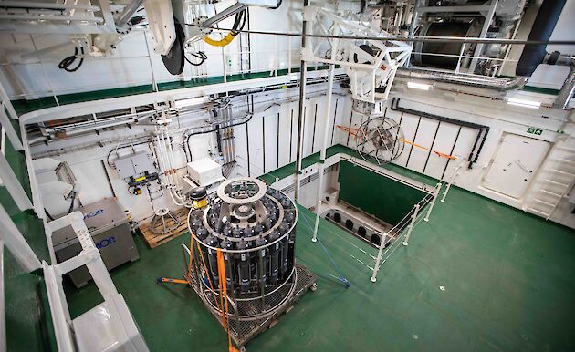 The moon pool room on the ship showing the open shaft and an oceanographic instrument.