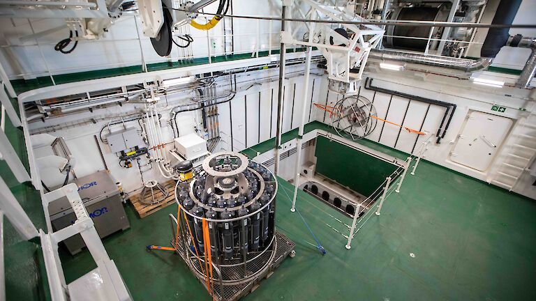 The moon pool room on the ship showing the open shaft and an oceanographic instrument.