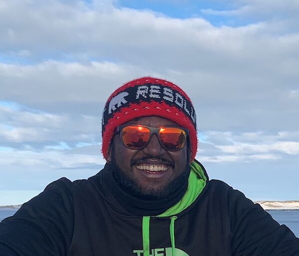 Close up of a man wearing a beanie, sunglases and hoodie