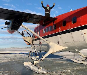 A man standing on the wing of a Basler aircraft parked on the sea ice