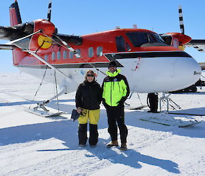 A man and woman on the sea ice in front of a twin otter plane
