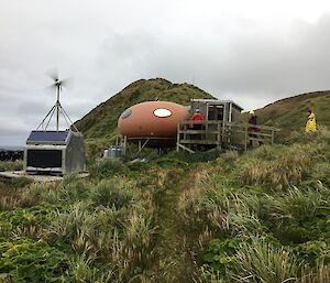 A round red hut and a wind generator used to power it