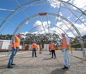 people in high-vis standing under metal framework