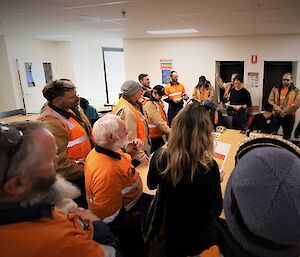 A group of station members gathered around a large table, receiving instructions from one of the Incident Management Team