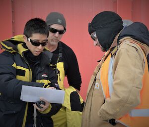 A few members of a search team studying a map of the station