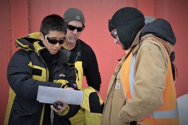 A few members of a search team studying a map of the station
