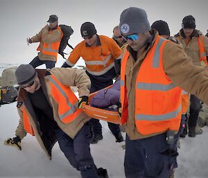 The found person has been placed on a stretcher and is being carried back to station by the Search and Rescue Team