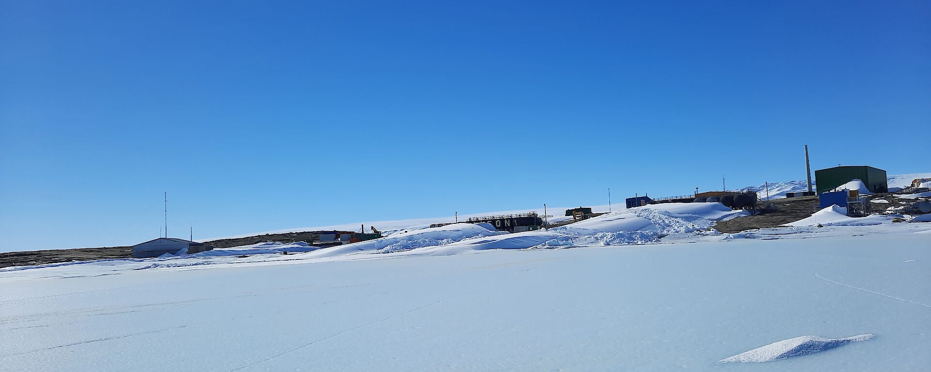 Mawson station with a covering of snow an big blizztails on a blue sky day