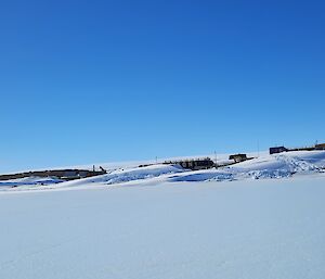 Mawson station with a covering of snow an big blizztails on a blue sky day