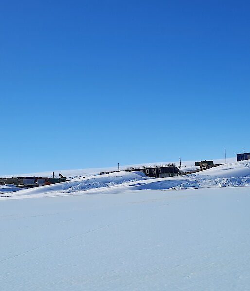 Mawson station with a covering of snow an big blizztails on a blue sky day