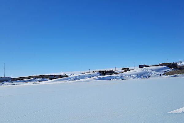 Mawson station with a covering of snow an big blizztails on a blue sky day