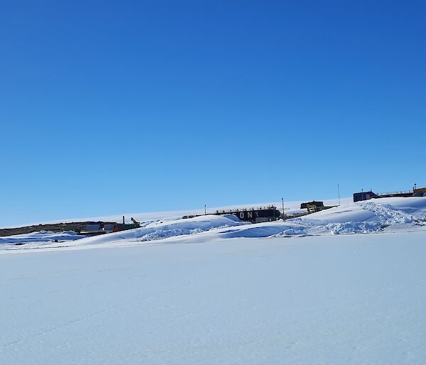Mawson station with a covering of snow an big blizztails on a blue sky day