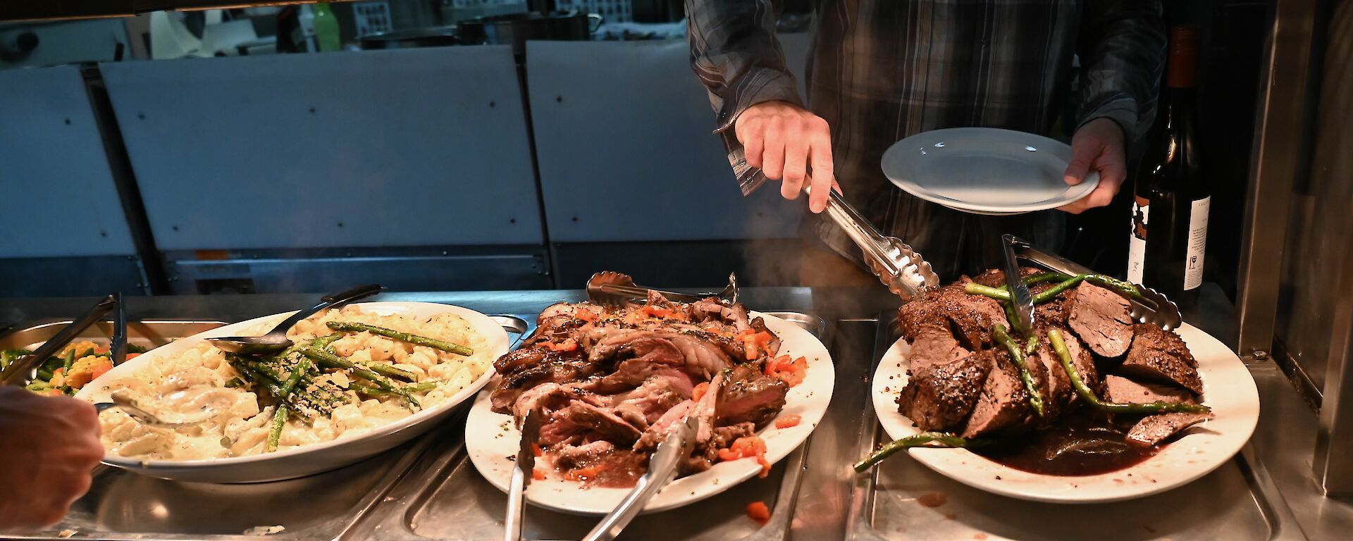 A diner serving himself from serving dishes laden with well-prepared food.