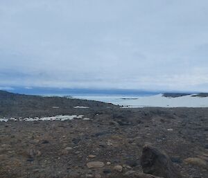 Landscape of rocky ground, snow on the horizon and a cloudy sky