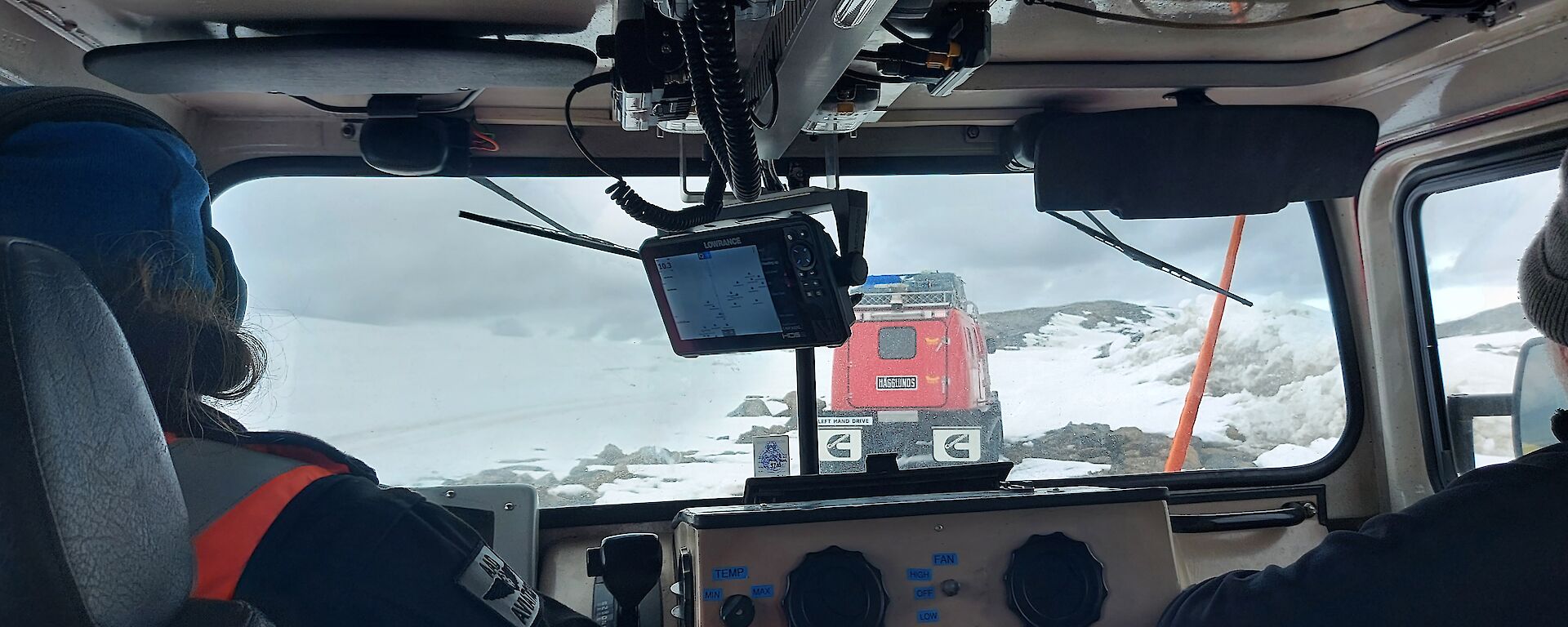 The view from the back seat of a Hägglunds, 2 people in the front seat