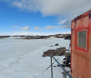 A red hut looking out over snow and rocky hills