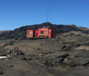 A small red hut on rocky hills