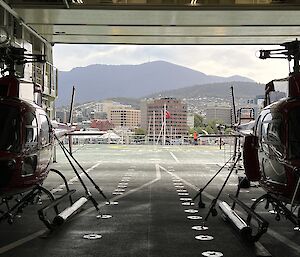 helicopters in hangar, city in background