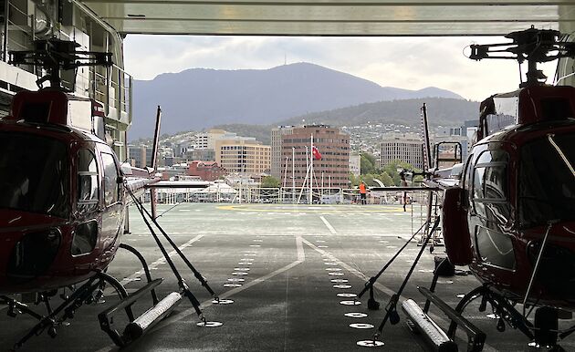 helicopters in hangar, city in background