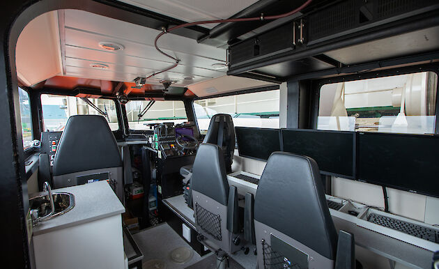 Interior of a small vessel kitted out with seats and screens.