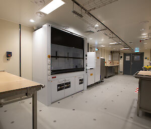 A brightly lit room contains benches and scientific equipment.