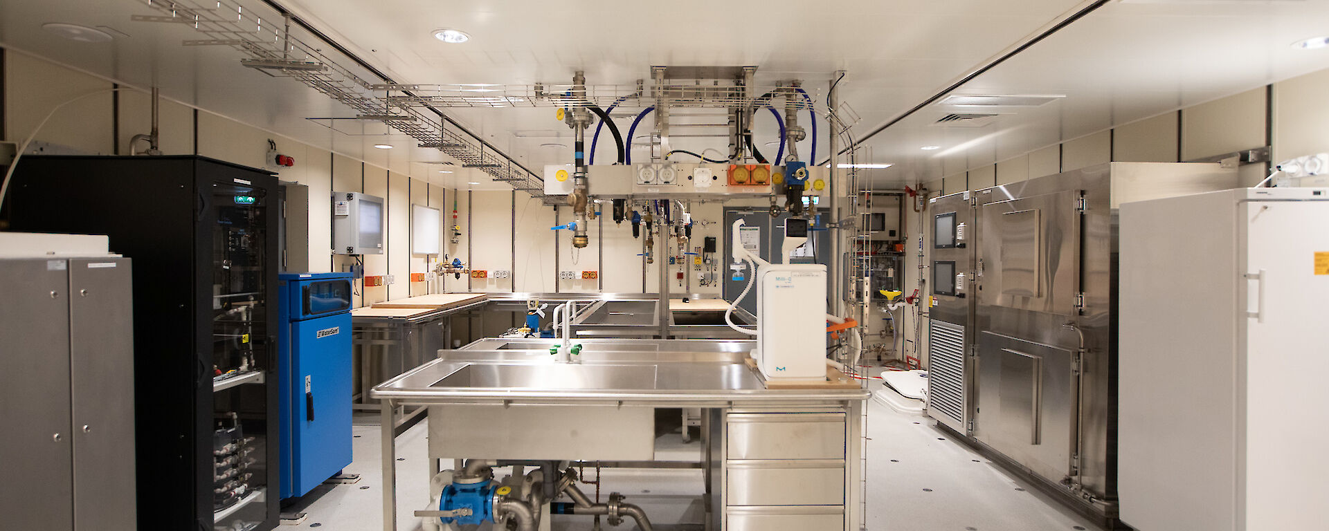 A brightly lit room contains sinks, desks, cabinets and scientific equipment.