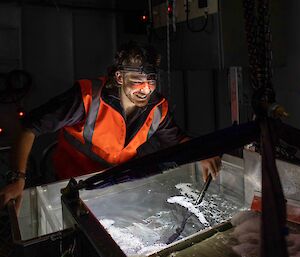 man with head torch examines tank of seawater