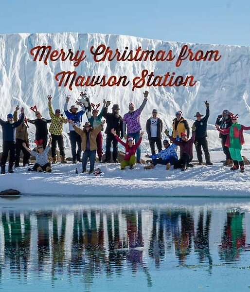 The Mawson team in Christmas gear at the base of West arm with sea ice and ice cliffs in the background