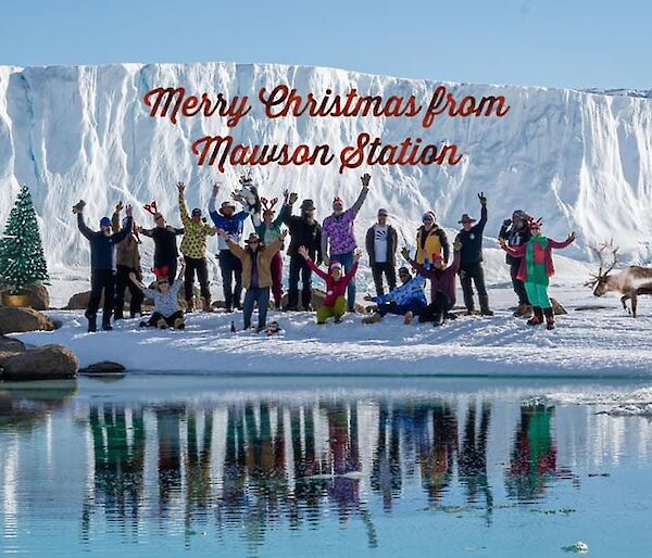 The Mawson team in Christmas gear at the base of West arm with sea ice and ice cliffs in the background