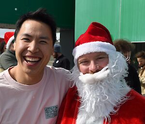 Man dressed as Santa Claus standing next to a smiling man