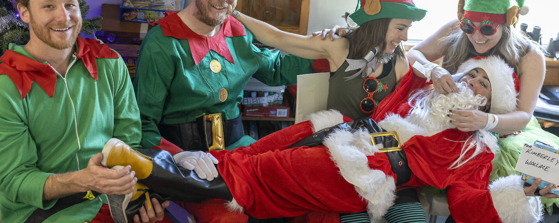 Five people dressed as elves and Santa relax after Christmas lunch