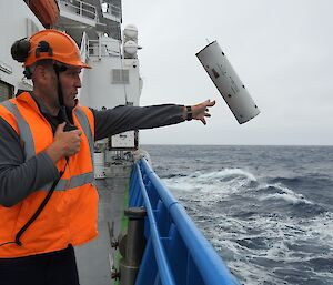 man in hi-vis drops device from ship