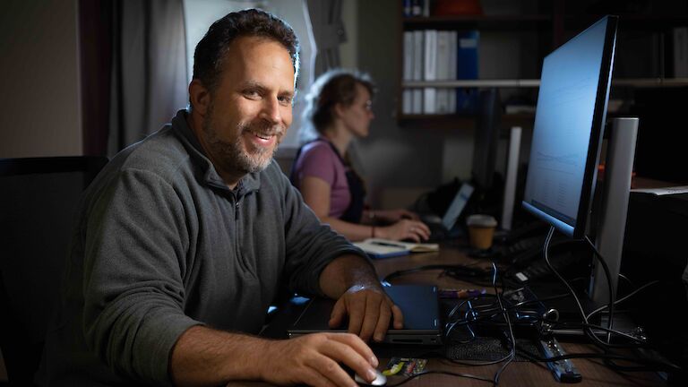 man at computer in room on ship