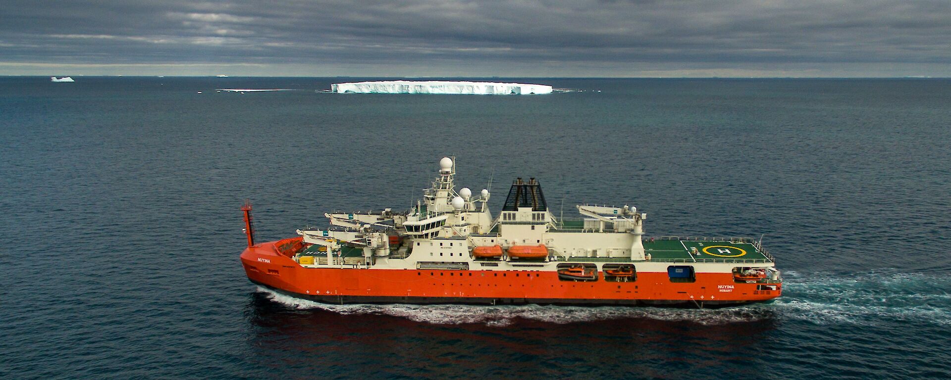 ship at sea with iceberg in background