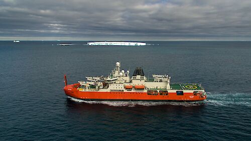 ship at sea with iceberg in background