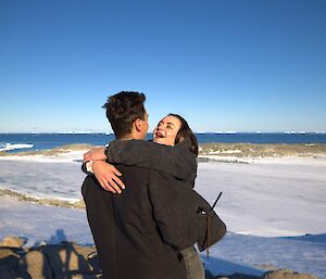 The young woman, accepting the proposal, laughs as she embraces her fiancé