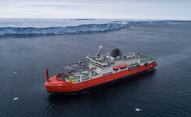aerial view of ship near ice cliff