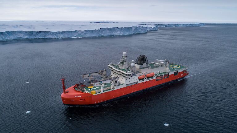 aerial view of ship near ice cliff