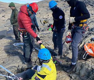 A group of people in harnesses working together to abseil a rocky outcrop