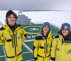 three people on ship moving through ice