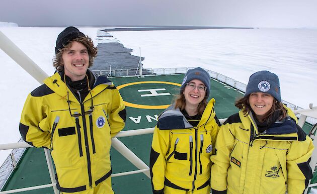 three people on ship moving through ice