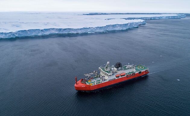 ship on ocean near ice cliff