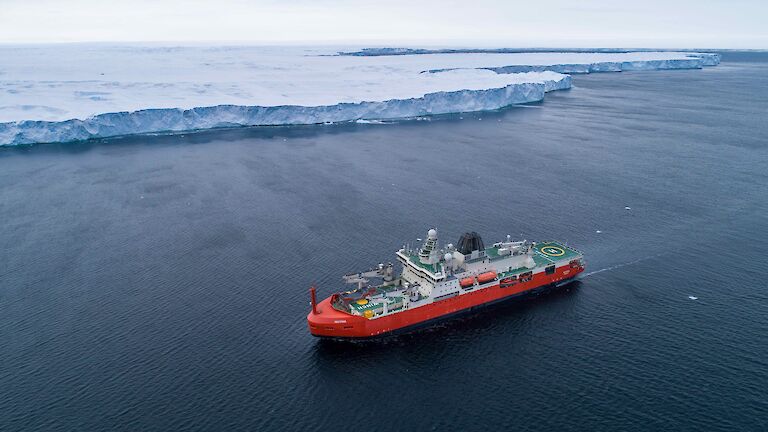 ship on ocean near ice cliff