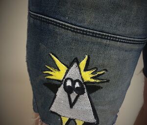 A cartoon character has been stitched on to the pocket of a pair of blue shorts