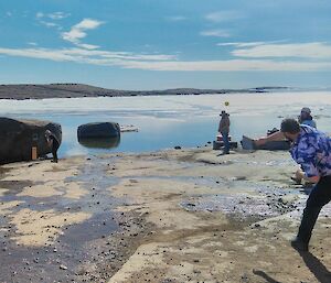 Expeditioners playing cricket on the rocky shorefront at Mawson for Australia Day