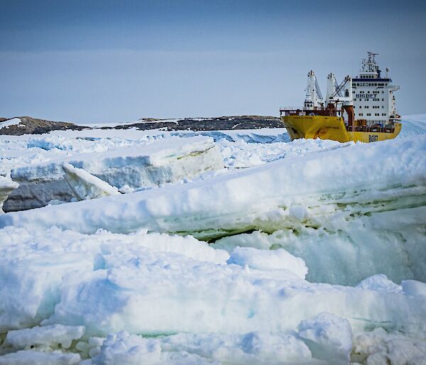 A cargo transport ship, surrounded by large chunks of sea ice