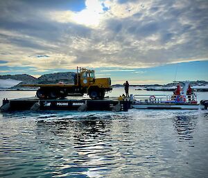 A Mack truck on a barge being transported across the water